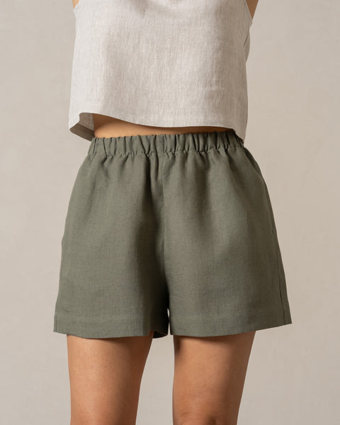 Linen pull-on shorts in the color stone green. High-waisted casual shorts with pockets and elastic waistband.
