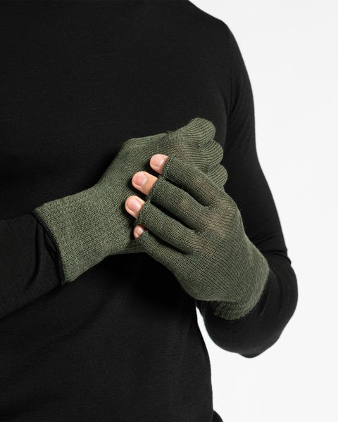 A person wearing a black long-sleeved shirt is shown from the chest up, putting on dark green fingerless gloves. The background is white.