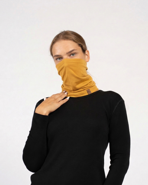 Woman wearing yellow merino wool long neck gaiter covering face, breathable wool accessory for running and outdoor activities.