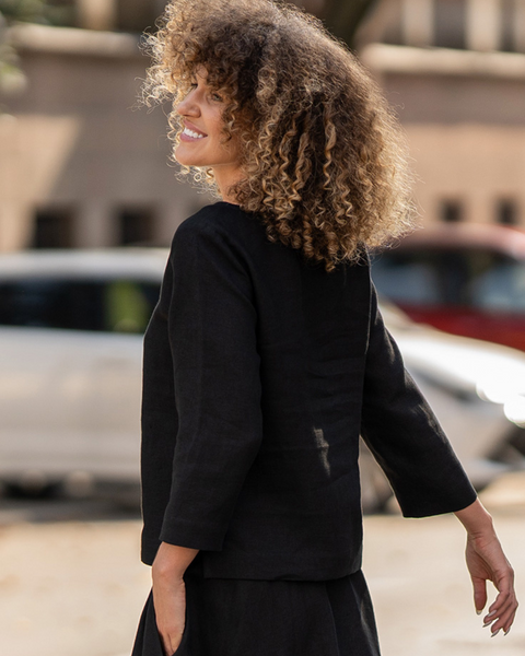 Woman in a black outfit walking outdoors with blurred background