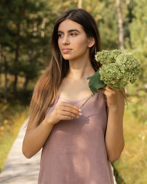 Woman gazing into something and wearing faded rose linen dress