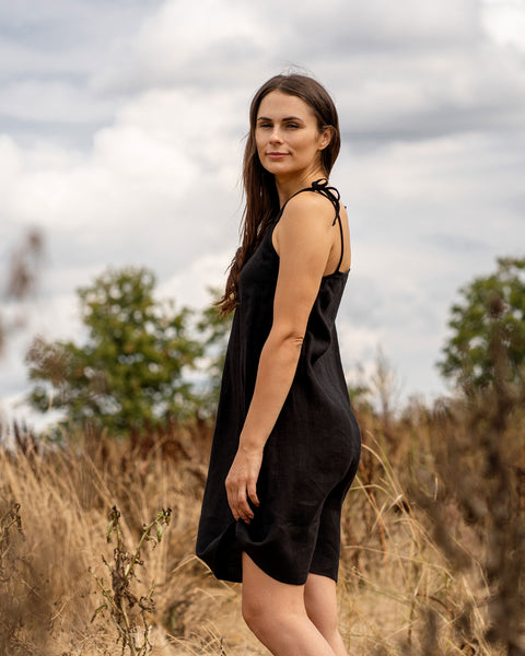 Woman standing outdoors and wearing black linen slip dress