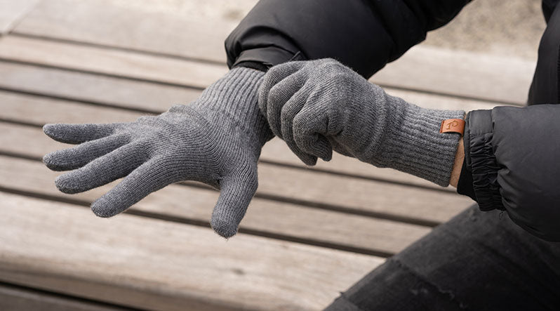 Man outdoors with dark gray knitted merino wool gloves.