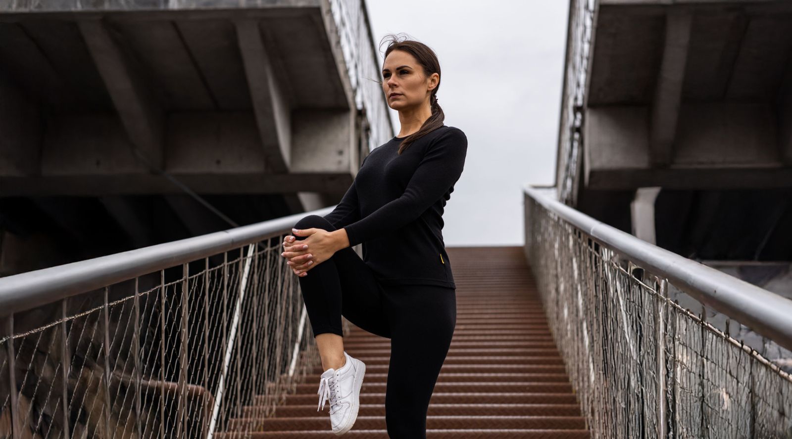 Woman sitting outdoors and wearing red leggings and black long sleeve top