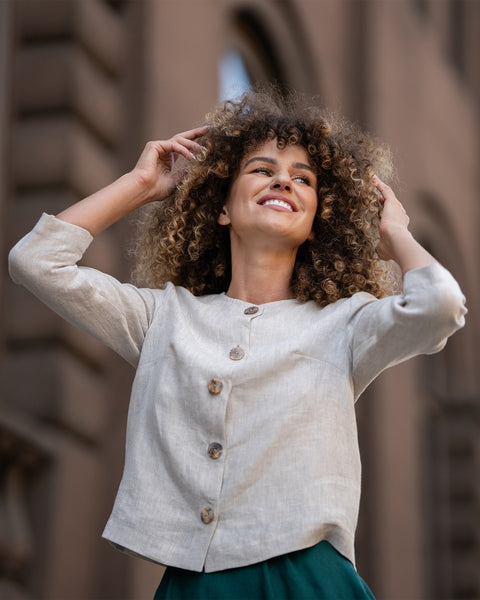 Close-up of a natural beige linen jacket showcasing its lightweight texture, button closure, neatly tailored collar, and 3/4-length sleeves
