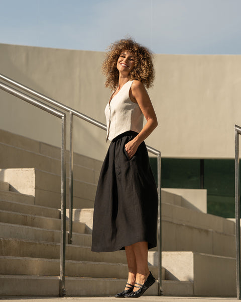 The menique women&#39;s linen est AVA in natural color and balck Sophia skirt. The woman is smiing