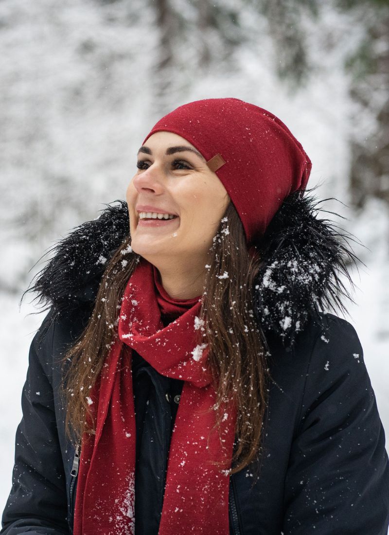 Woman wearing a red beanie and scarf in a snowy outdoor setting