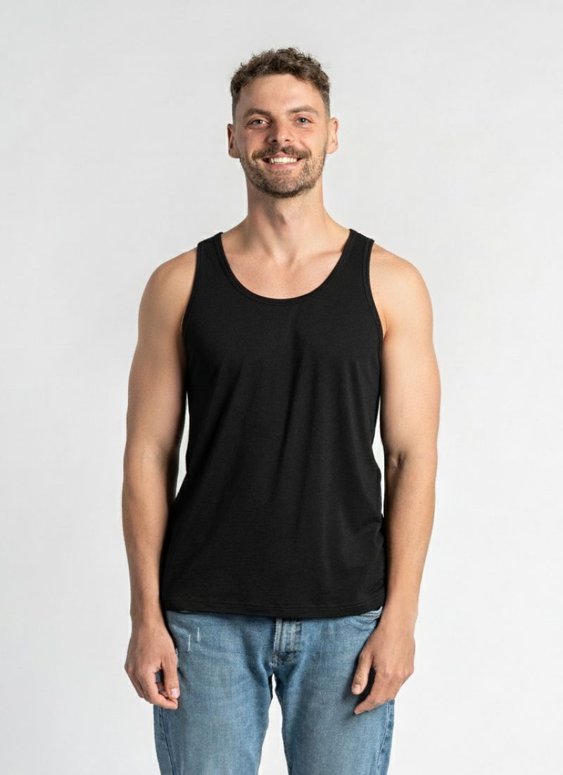 Man wearing a black tank top and blue jeans against a plain background