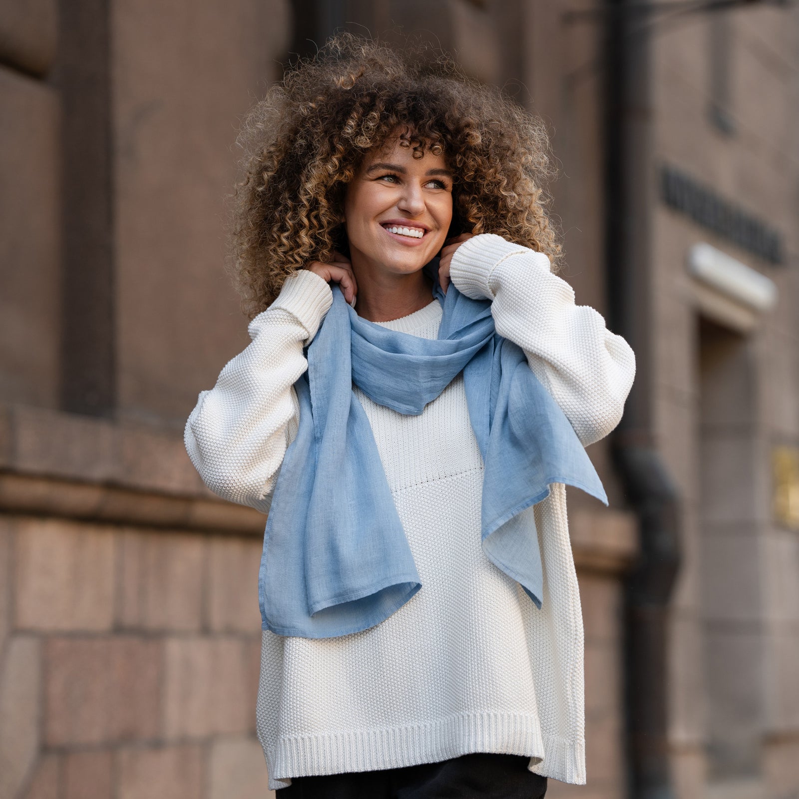 Women wearing Linen Scarf in Cloudy Blue color while in the background is seen palm trees