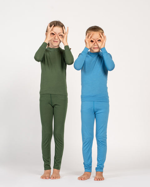 Two children wearing green and blue pajama sets on a white background