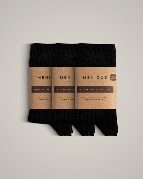 A 3-pack of kids’ black ribbed merino wool socks, folded and wrapped in brown kraft paper labels labeled “Menique Premium Quality.