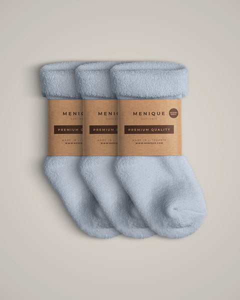 A 3-pack of kids’ light blue sherpa-lined merino wool socks with Menique branding.