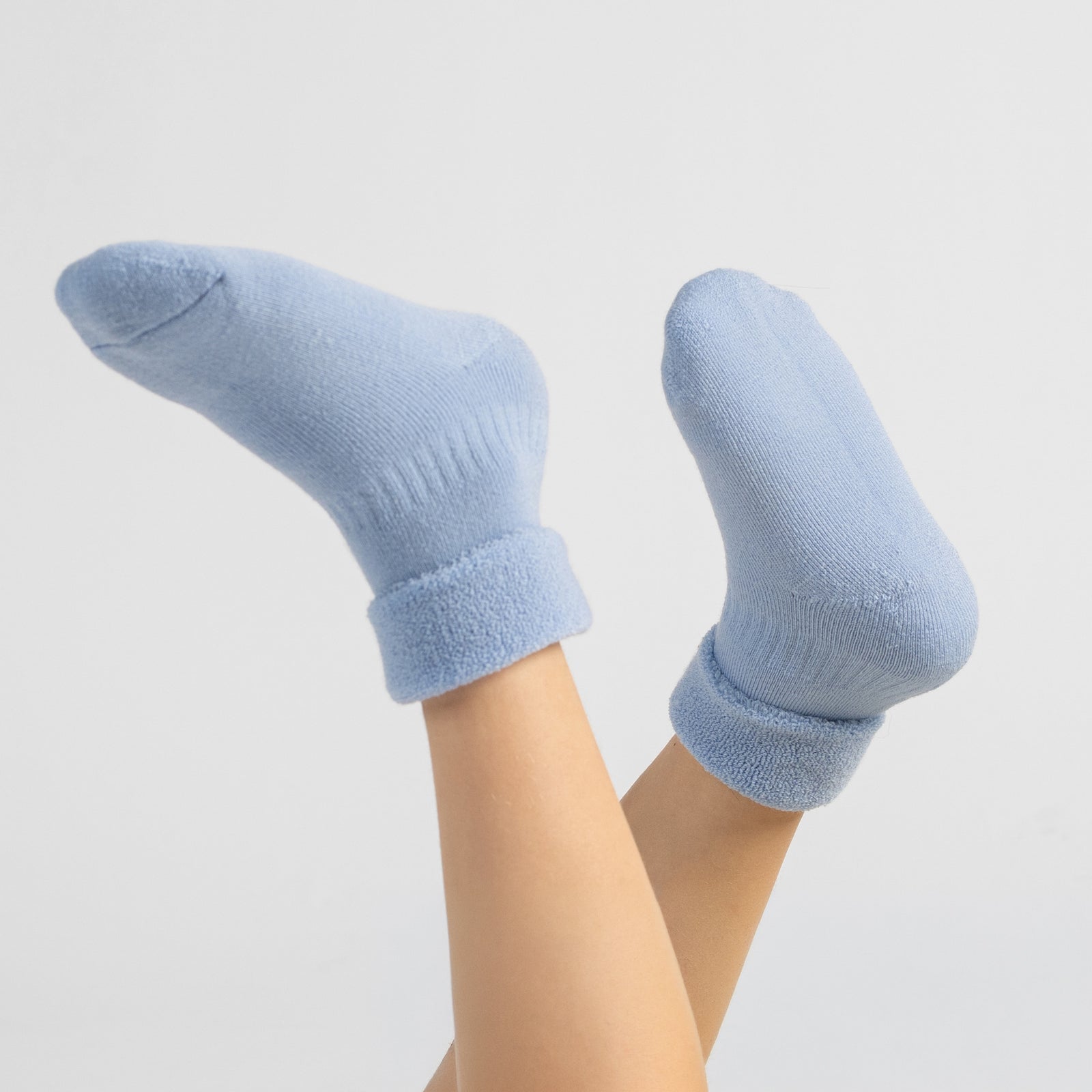 Set of six pairs of light blue sherpa-style children’s socks, bundled together with Menique eco kraft paper wraps reading ‘Premium Quality.