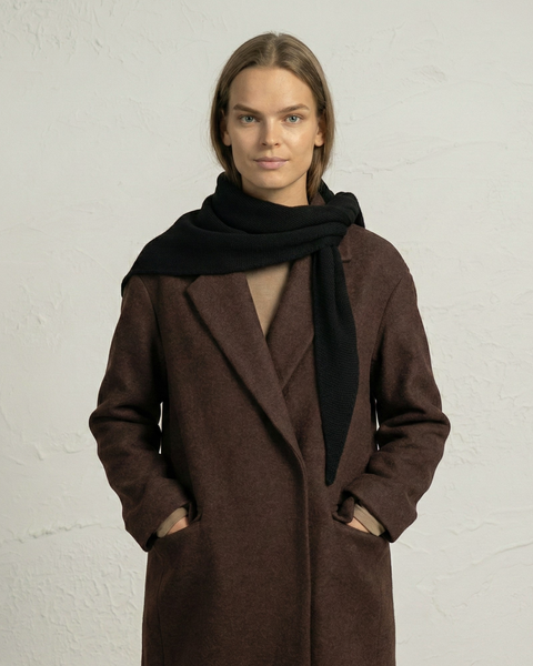 Woman wearing a black merino knit bandana scarf with a brown coat