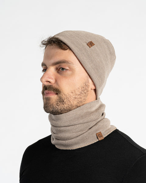 Man wearing a creamy beige merino wool knit beanie and scarf set on a white background