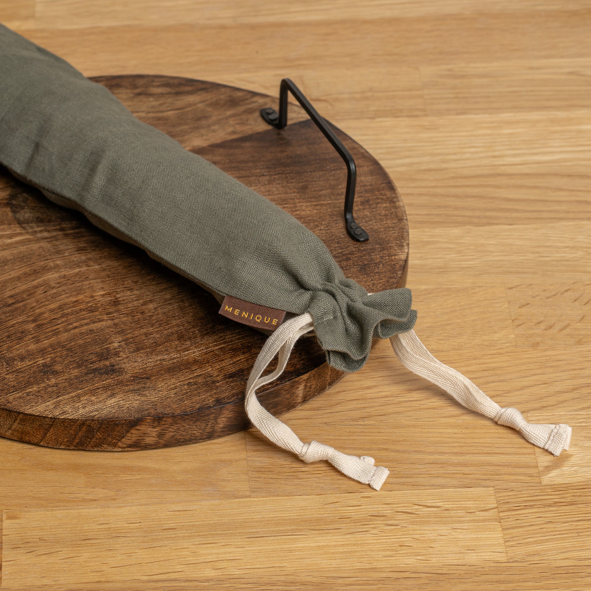 Long Bread bag hanging on a hook with bread and kitchen items on a table.