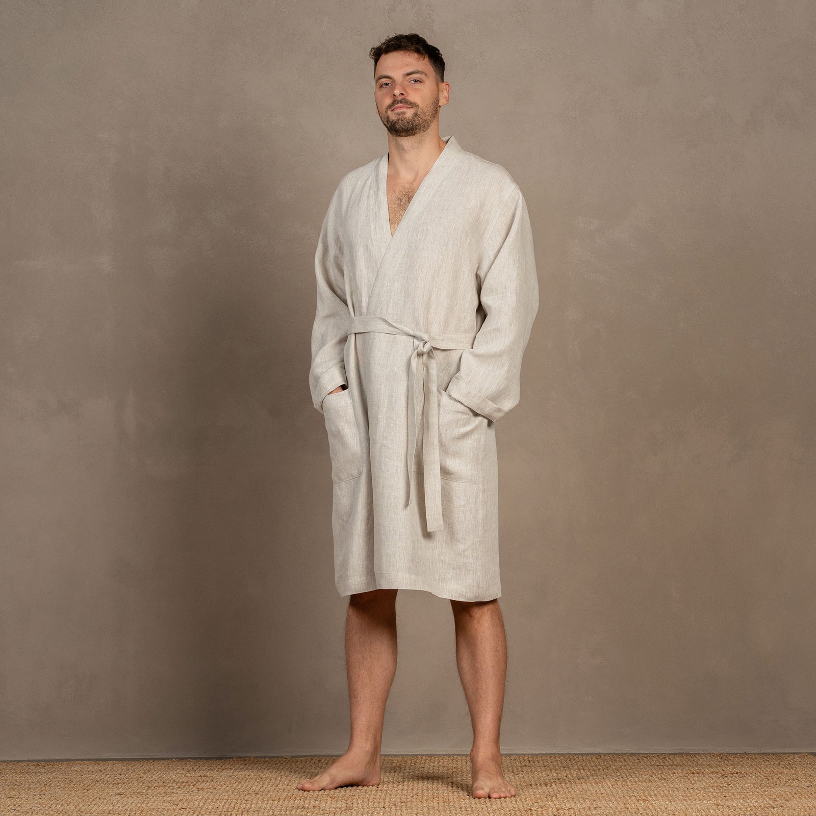 A man wearing the cobalt blue menique linen bathrobe. The bathrobe has pockets on the sides and a tie at the front.