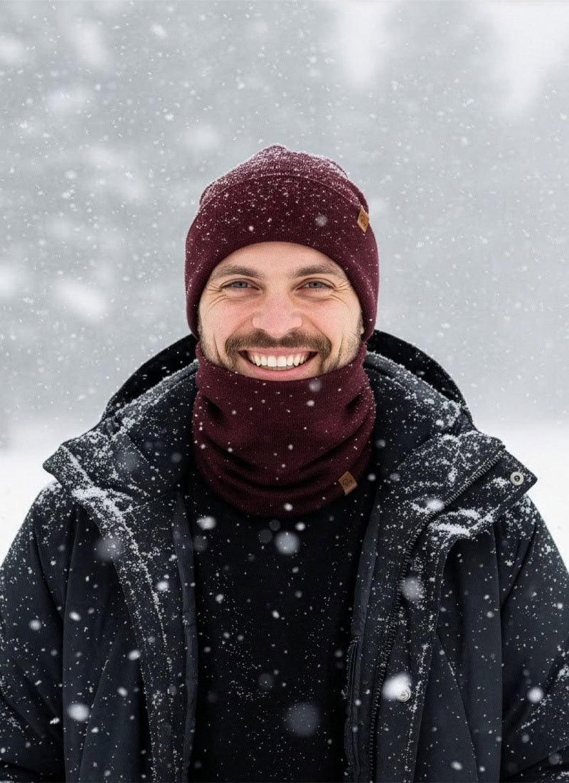 Man wearing a maroon beanie and scarf in a snowy landscape