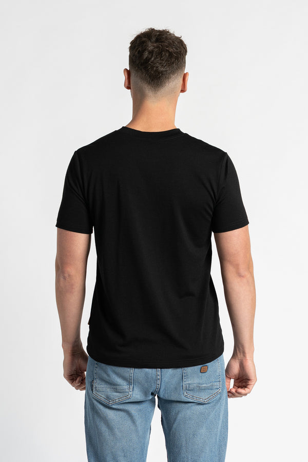 Back view of a man wearing a black t-shirt and light blue jeans, standing against a white background. The black t-shirt is the primary focus, showcasing its regular fit and design from the rear. The man is positioned centrally, displaying the back of the garment clearly.
