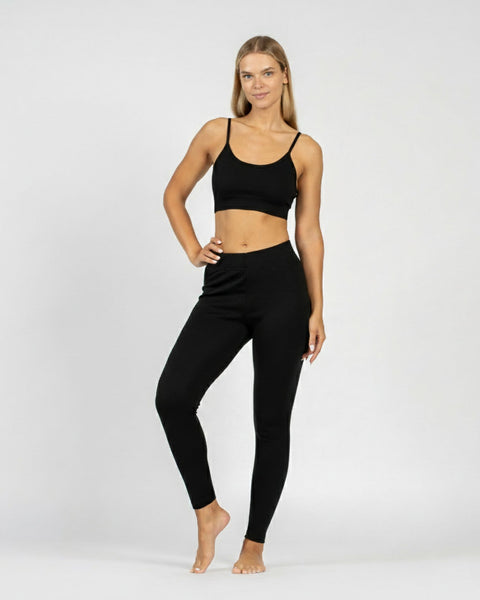 Woman wearing a black sports bra and leggings on a white background