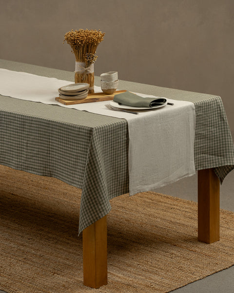The natural linen table runner on top of a wooden table, captured in a close up picture from the corner of the table. 