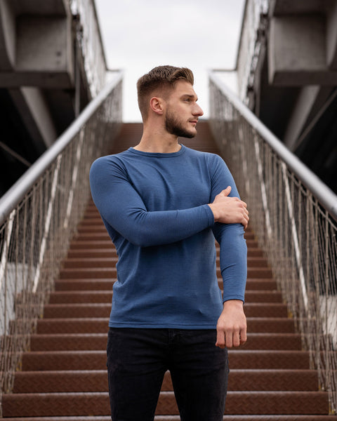 Man wearing a blue long-sleeve shirt standing on a staircase