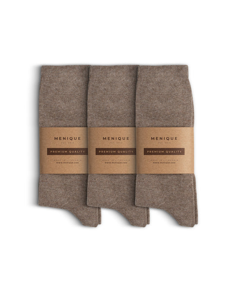 Set of three pairs of cotton socks, neatly folded and wrapped with Menique’s minimalist brown kraft paper packaging labeled ‘Premium Quality.