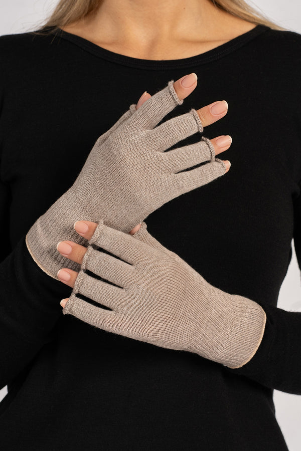 Close-up of a woman’s hands wearing creamy-beige fingerless merino gloves, palms facing inward and fingers visible.