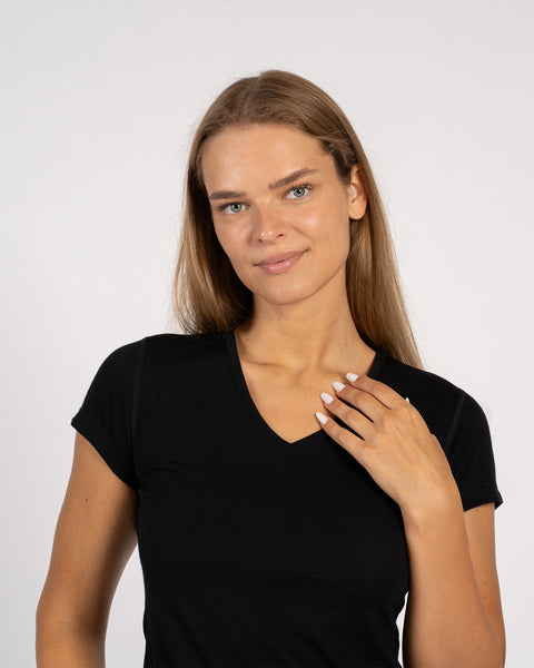 A closer front shot of a woman wearing a black t-shirt, resting one hand near her collarbone.