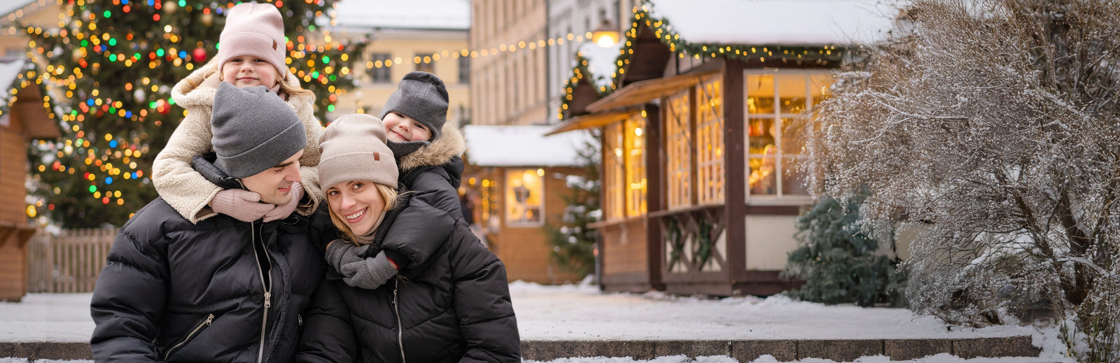 Family posing outdoors in a snowy village setting with Christmas decorations.