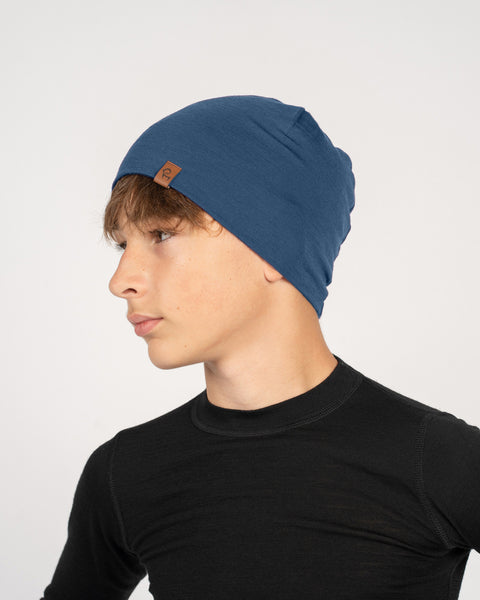 Teen boy wearing a blue Merino wool beanie and black base layer, showcasing a soft and comfortable fit.