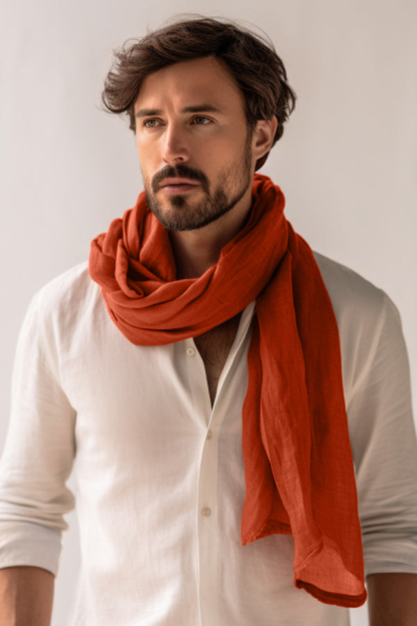 Man wearing a white shirt and orange scarf against a plain background