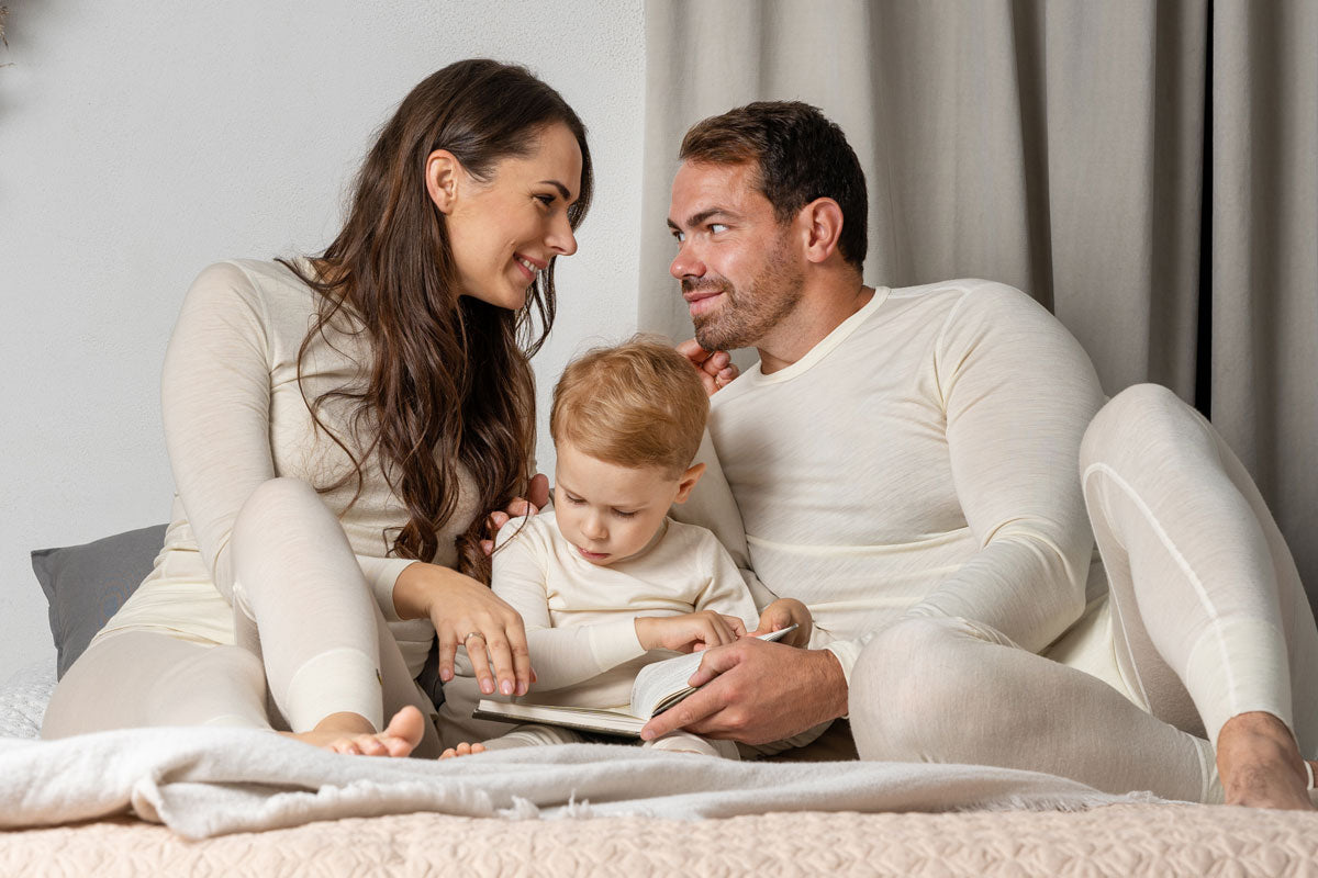 Family on the bed wearing matching pajamas from Merino wool