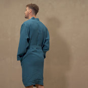 A man showing menique linen robe in the color cobalt blue. Man is turning around and touching robe sleeves. 
