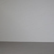 A woman with long, curly brown hair smiles and models a sleeveless, dark green maxi linen dress against a textured gray backdrop in a short video. They turn to the side, showing the flow of the dress.