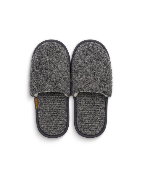 A top-down view of a pair of dark gray fuzzy slip-on slippers with textured gray insoles and a "MENIQUE" tag on the side of the left slipper.