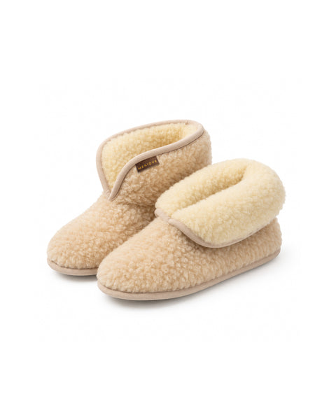 An angled view of a pair of beige fuzzy ankle bootie slippers. The right slipper has its cuff folded down to reveal a plush cream-colored interior lining, and a "MENIQUE" tag is visible on the edge.