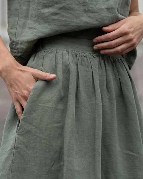Close-up of a woman putting her hand in stone green linen skirt pocket.