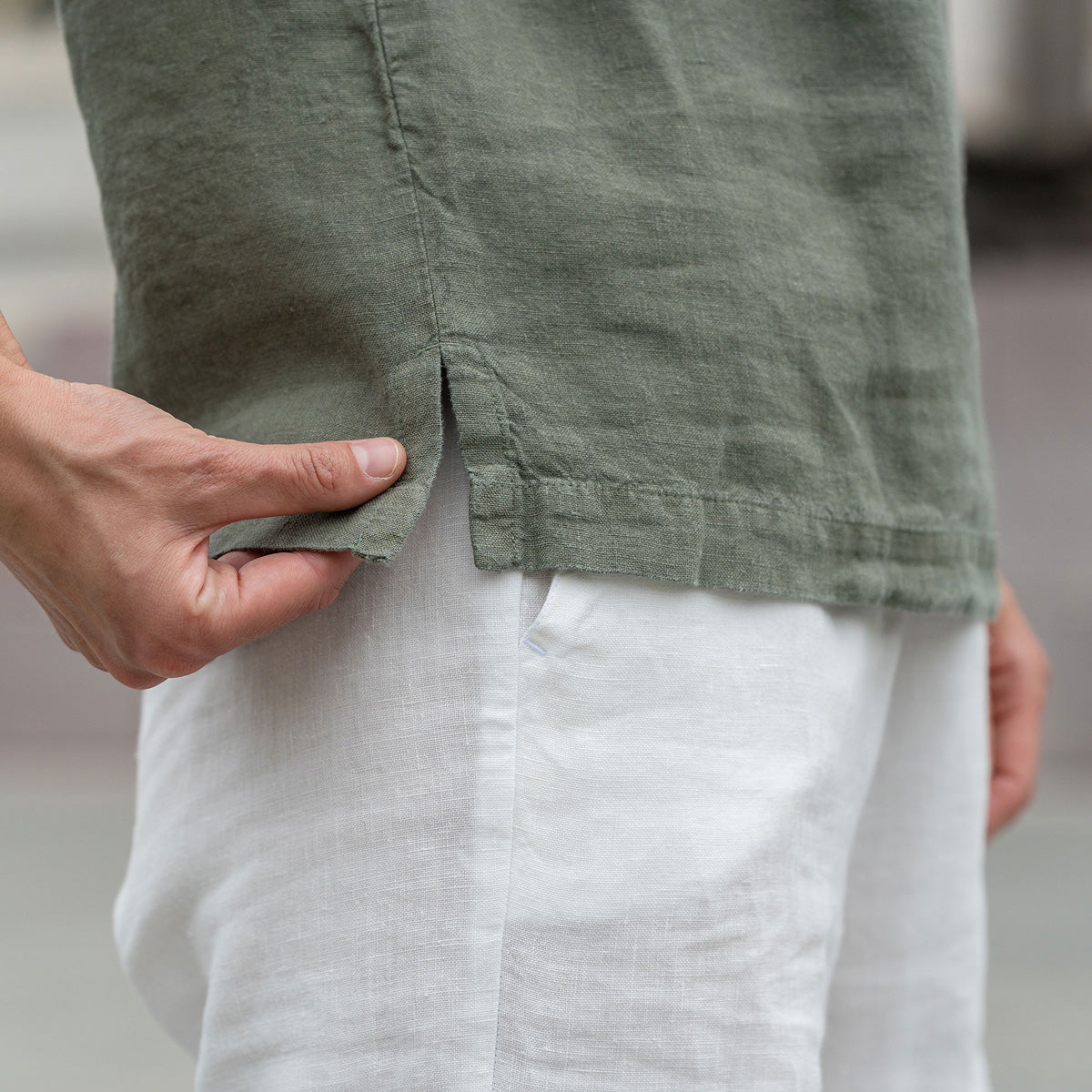 Beautiful woman with a curly hair in the city, posing wearing stone green linen blouse Emma and pure white linen pants Dakota.