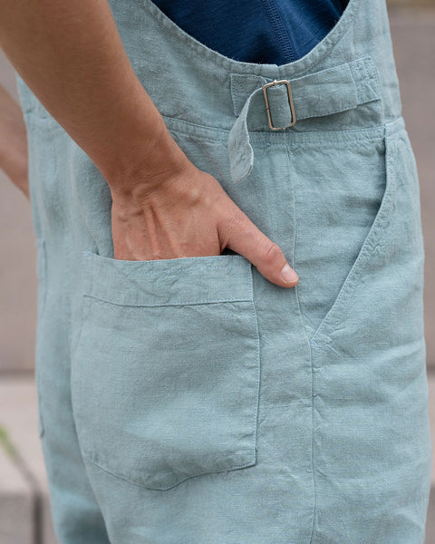Close-up of a woman&#39;s hands inside linen jumpsuit back pockets.