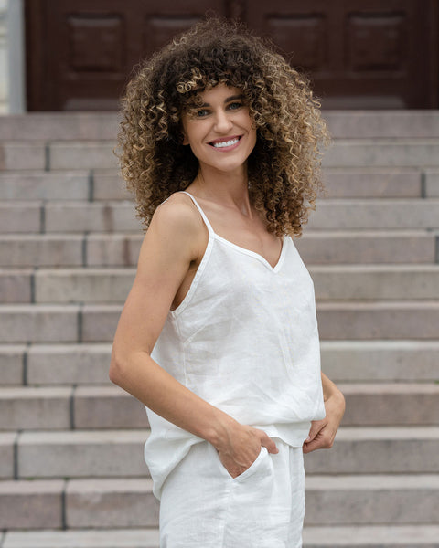 Beautiful woman posing in a city. Wearing pure white linen slip top and pure white linen pants.