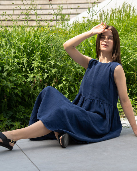 Young woman posing in a city, wearing linen smock dress Maya in a Storm blue cover.