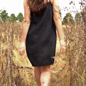 Woman walking through tall grass while wearing black linen dres